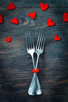 Two forks on a table surrounded by hearts for Valentine's Day