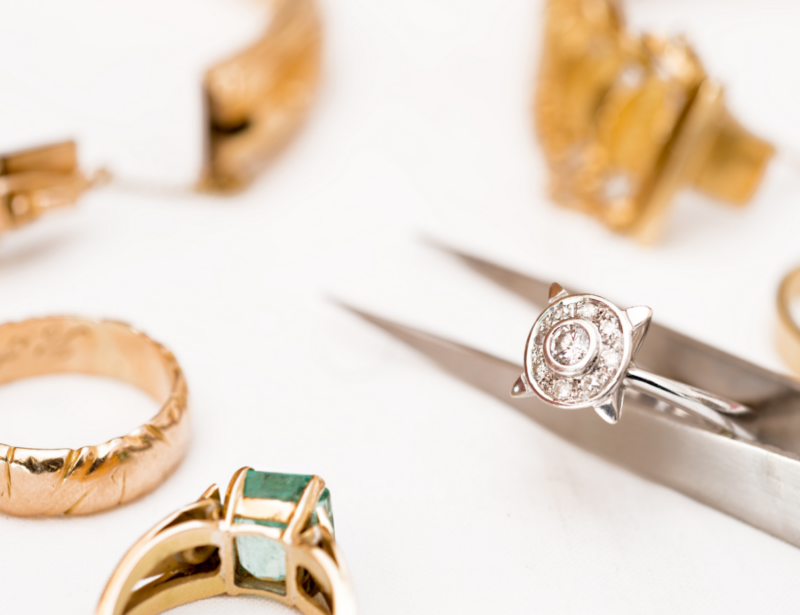 Scattered jewelry is displayed while a ring is being analyzed for a jewelry appraisal.