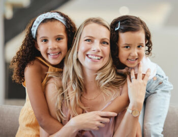 Portrait of mother with kids in home, bonding and hugging. Mother has on necklace, watch, and rings.